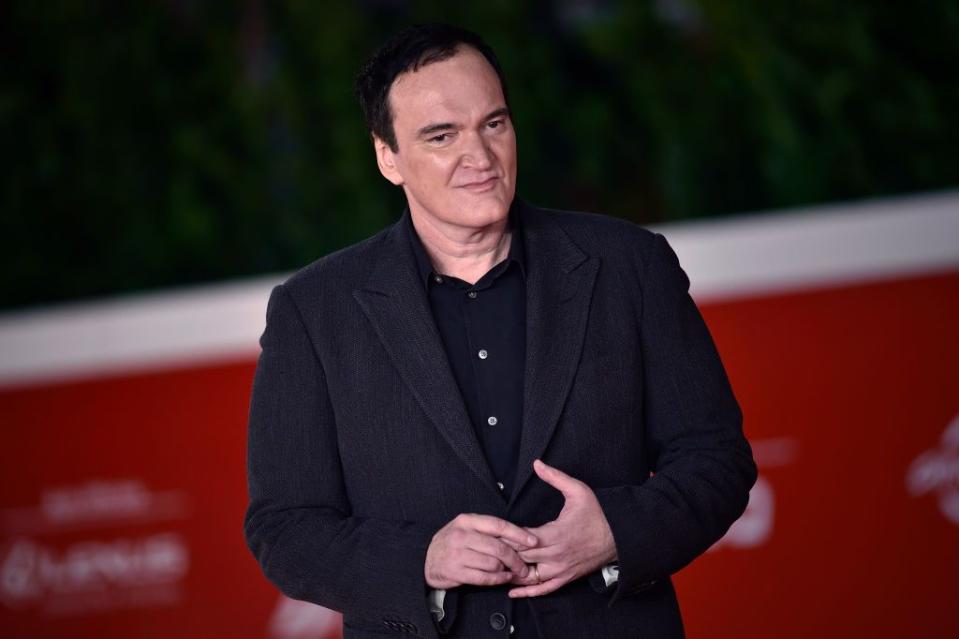 quentin tarantino standing on a red carpet and clasping his hands