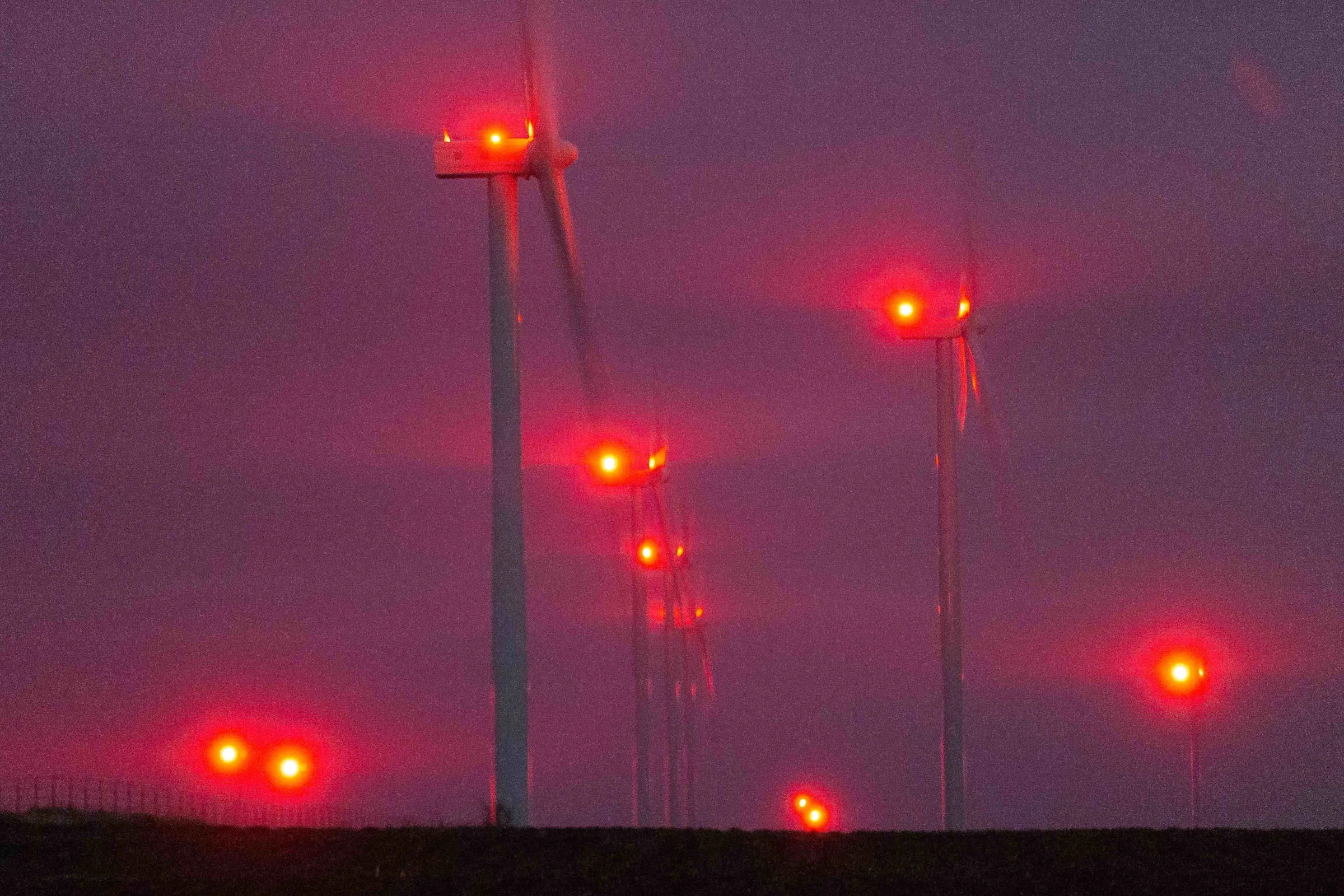 Red lights on wind turbines in Allen County flash in unison Thursday night during an overcast sky. A bill in the Kansas legislation would make these lights less intrusive by requiring light mitigation technology on new and existing wind farms.
