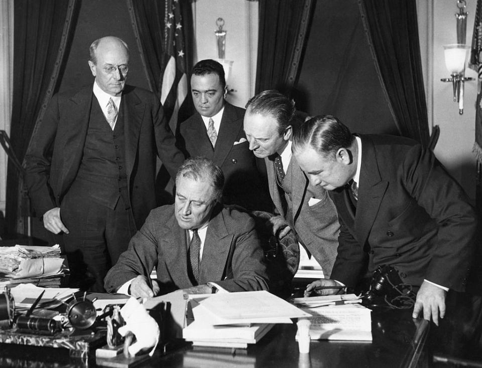 FBI Director J. Edgar Hoover stands behind President Franklin Delano Roosevelt and watches him sign a bill to enforce the fight against crime.<span class="copyright">Bettmann Archive</span>