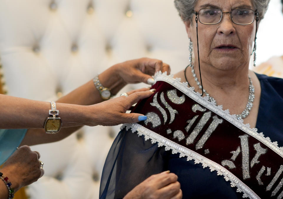 Las princesas ajustan la banda a Nelly I, luego de que fuera coronada como Reina Mayor de la Primavera en La Paz, Bolivia, el jueves 21 de septiembre de 2023. (Foto AP/Juan Karita)