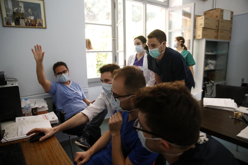 In this photo taken on Friday, May 8, 2020, ICU consultant Marios Karvouniaris, left, and internal medicine Agamemnon Bakakos, center, show medical students a CT of a patient at the COVID-19 Clinic of Sotiria Hospital in Athens. Greece's main hospital for the treatment of COVID-19 is also the focus of a hands-on training program for dozens of medical students who volunteered to relieve hard-pressed doctors from their simpler duties while gaining a close peek at the front lines of a struggle unmatched in modern medical history. (AP Photo/Thanassis Stavrakis)