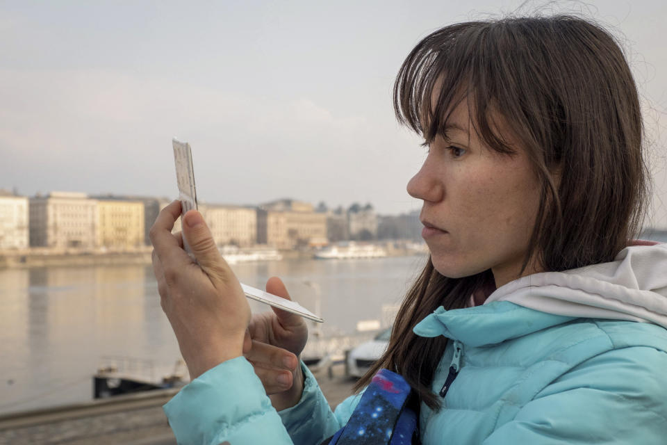 Olena, a Russian citizen fleeing from Kyiv, Ukraine (no family name given for safety reason) looks at herself in a mirror after arriving in Budapest, Hungary on Friday, March. 4, 2022. Olena who years ago left her home country in opposition to Vladimir Putin's government has been forced to flee again — this time from her adopted home of Kyiv — as Putin's armed forces assault Ukraine. (AP Photo/Balazs Kaufmann)