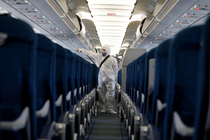 FILE PHOTO: A health worker sprays disinfectant inside a Vietnam Airlines airplane to protect from the recent coronavirus outbreak, at Noi Bai airport in Hanoi, Vietnam
