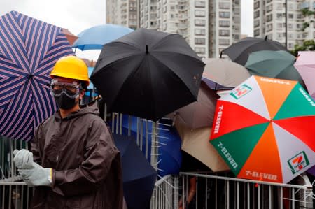 Anti-extradition bill protesters hold umbrellas to protect themselves as they face riot police after a march at Sha Tin District of East New Territories, Hong Kong