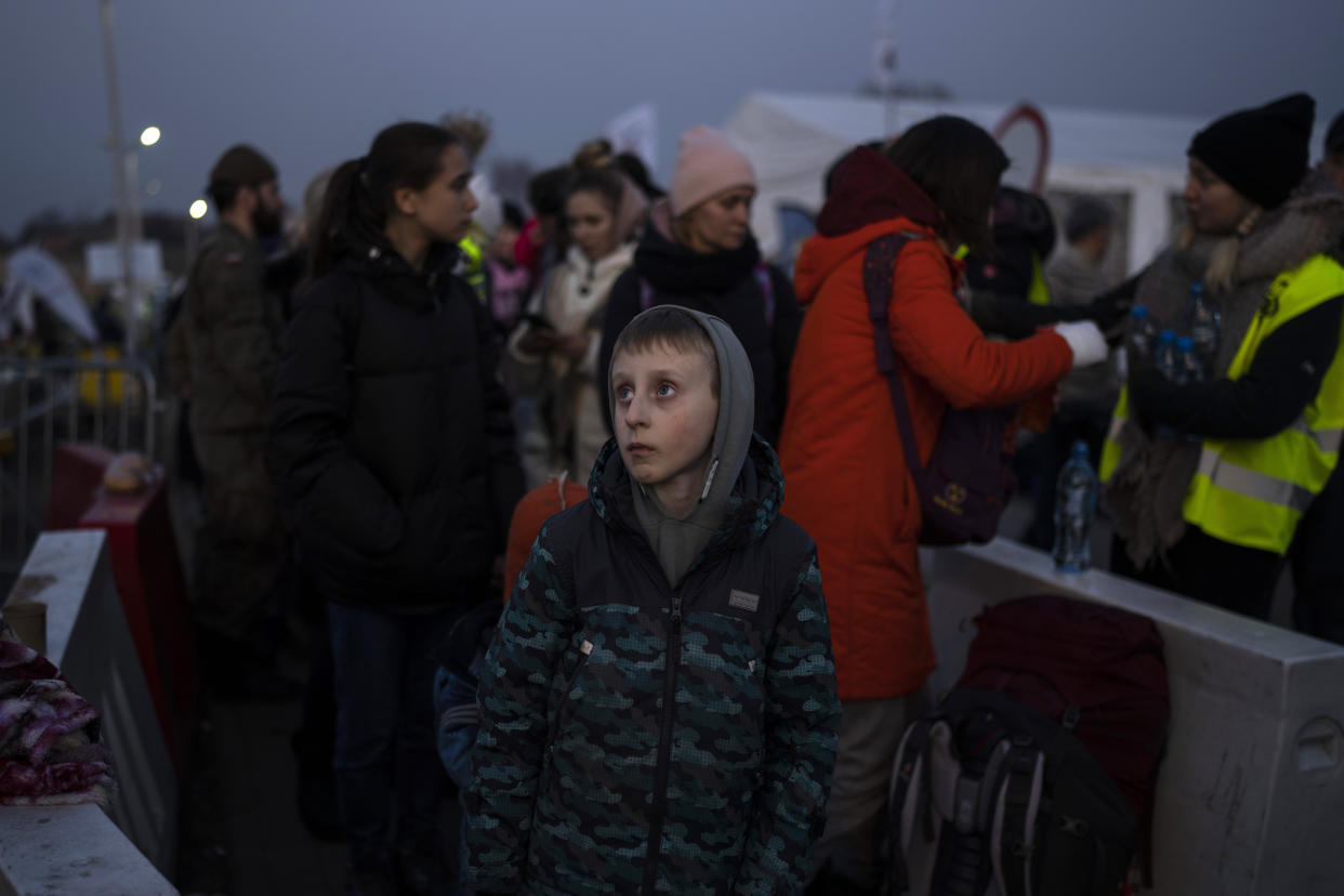 A boy stands with a group of people fleeing Ukraine as they stand in a line after arriving at the border crossing in Medyka, Poland, on Monday, March 14, 2022. Russia's military forces kept up their punishing campaign to capture Ukraine's capital with fighting and artillery fire in Kyiv's suburbs Monday after an airstrike on a military base near the Polish border brought the war dangerously close to NATO's doorstep. (AP Photo/Petros Giannakouris)