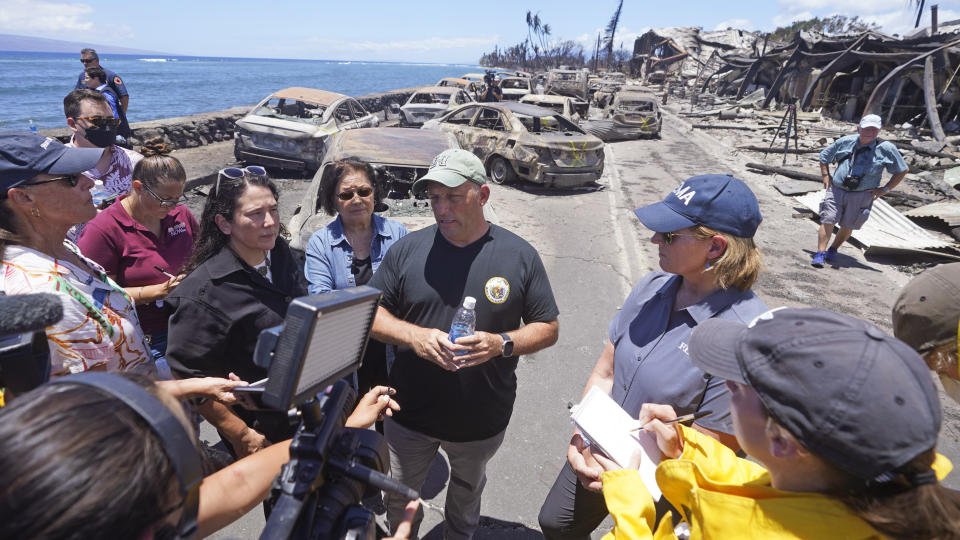 Hawaii Gov. Josh Green, center, speaks to reporters during a tour of wildfire damage on Saturday, Aug. 12, 2023, in Lahaina, Hawaii. (AP Photo/Rick Bowmer)