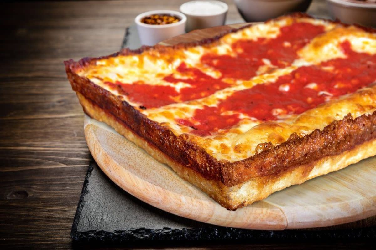 Cheese Detroit-style pizza, Buddy’s, Detroit, Michigan, selective focus, on a round wooden board, on rustic wooden table with condiments blurred in the background