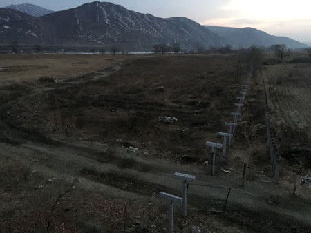 A barbed-wire fence separating North Korea from China is seen in this photo taken from the Chinese border city of Hunchun, China, March 18, 2015. REUTERS/Staff