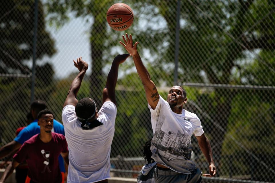 Two players reach for a basketball during a game