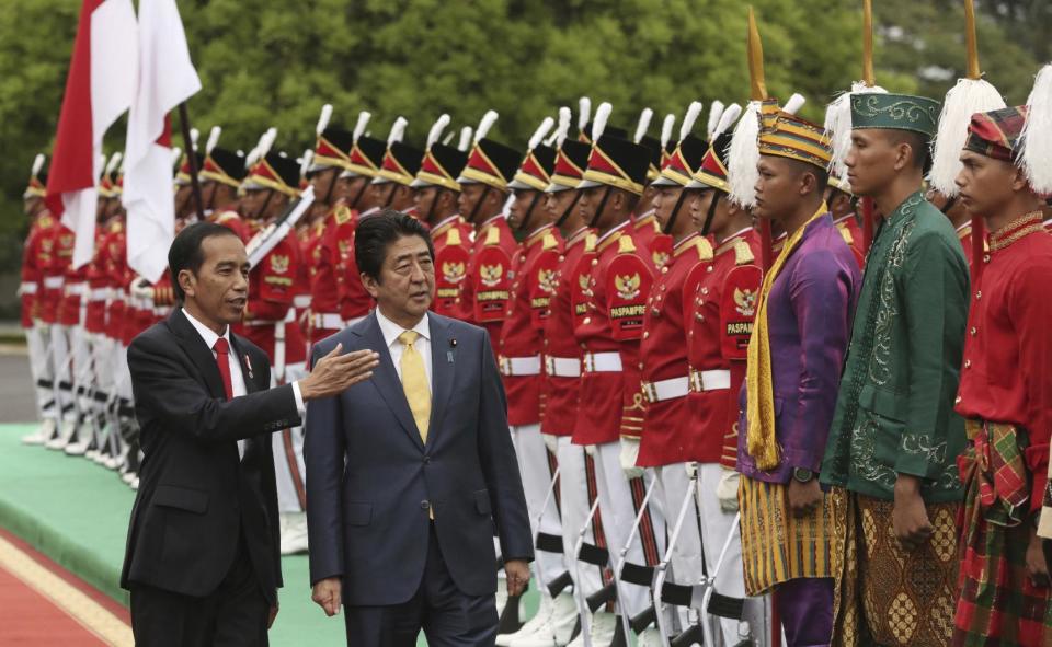 FILE - In this Jan. 15, 2017 file photo, Indonesia President Joko Widodo, left, talks to Japan's Prime Minister Shinzo Abe as Abe inspects an honor guard during a welcome ceremony at Presidential Palace in Bogor, West Java, during Abe's visit to Indonesia. China is not happy with Abe’s high-profile visits to the Philippines, Australia, Indonesia and Vietnam over concerns that he may be trying to pull the rug under Beijing’s efforts to pacify its neighbors in and around the South China Sea. (AP Photo/Achmad Ibrahim, File)