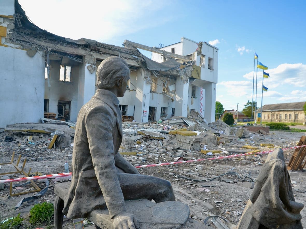 A statue sits, undamaged, outside the ruined Derchachi cultural centre, in northeast Ukraine. The building was hit by a Russian artillery strike and a missile early on Friday. (Murray Brewster/CBC - image credit)