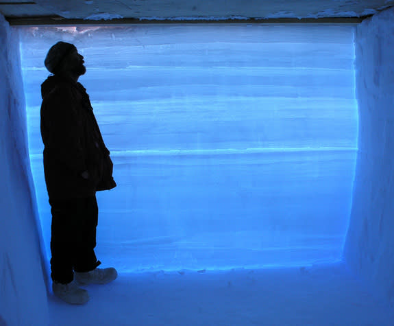 A West Antarctica Ice Sheet Divide project researcher stands in a snow pit next to an ice core with data from 68,000 years ago. The prominent line across the middle of the ice separates one year's ice and snow accumulation from the next year’s