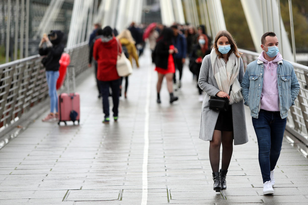 A couple wearing face masks keep on their side of the Golden Jubilee Bridge in London as the UK heads for another lockdown due to coronavirus.