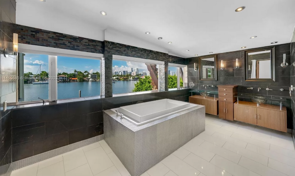 The master bathroom, pictured above, has a double sink, walk-in shower, and bathtub overlooking Biscayne Bay.
