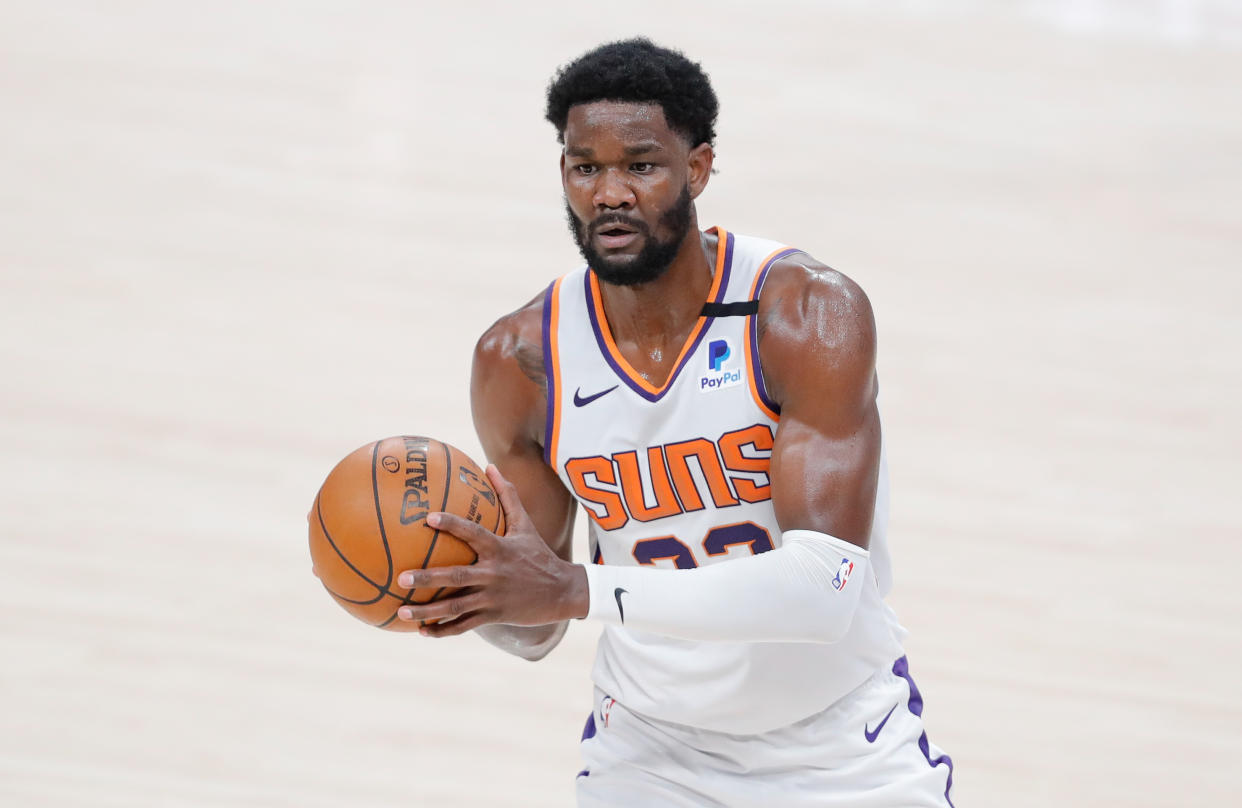 Deandre Ayton with the basketball in his hands looking to pass during a game.