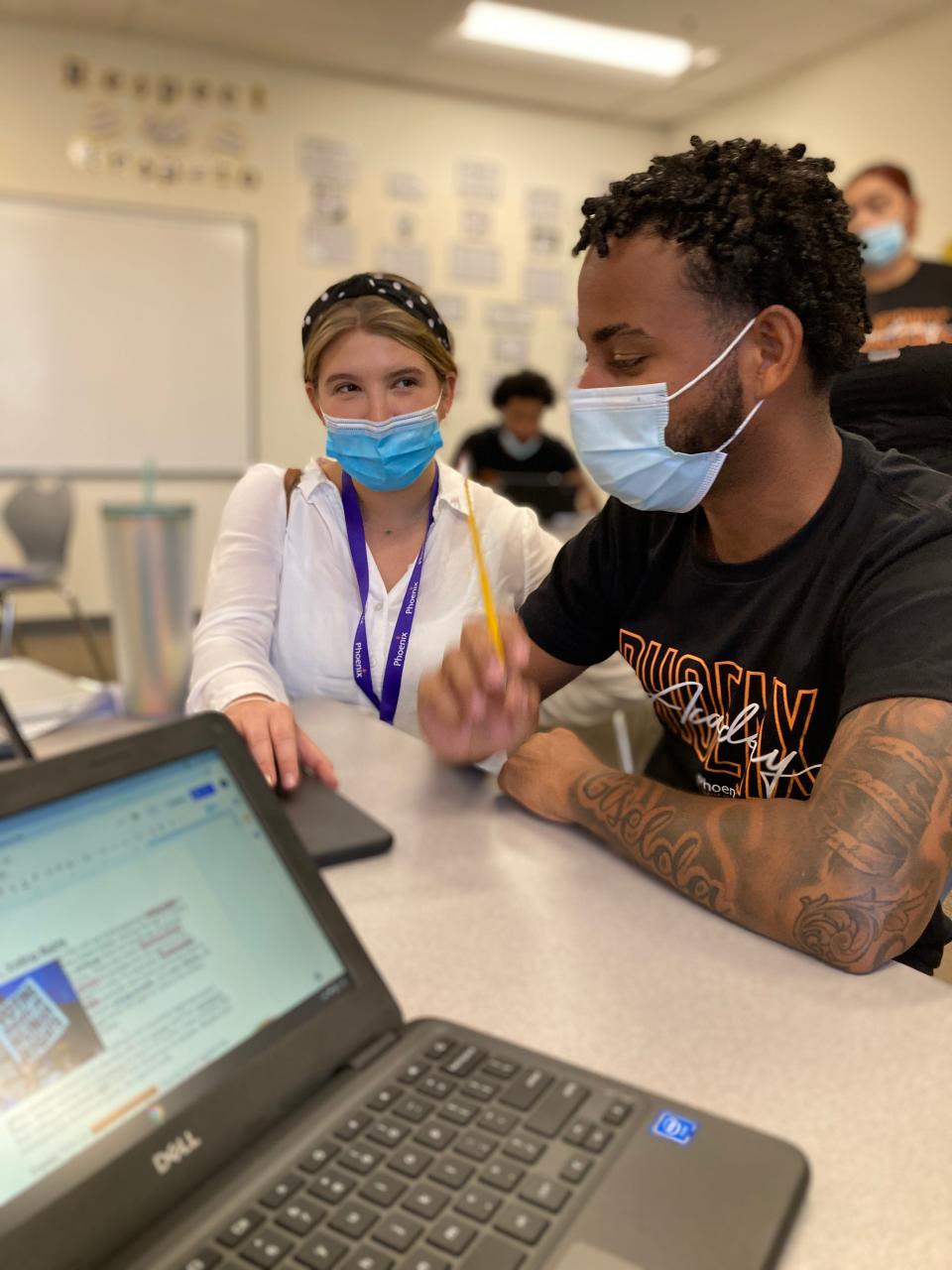 Lindsay Weinberg, a humanities teacher at Phoenix Charter Academy in Lawrence, Mass., helps a fourth-year student with a writing assignment in September. Phoenix Charter Academy's schools experiment with different schedules this year to help students get back on track.