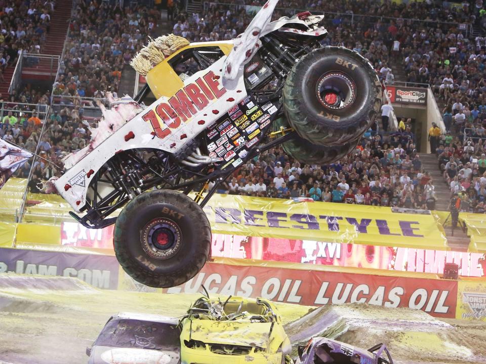 A photo of the monster truck zombie jumping over other cars