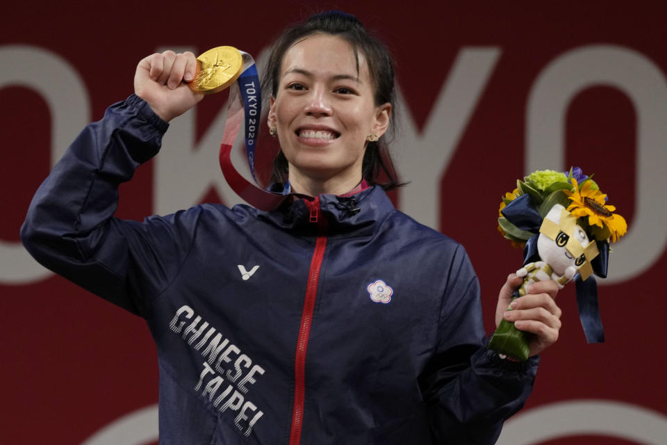 Kuo Hsing-Chun of Taiwan celebrates on the podium after winning the gold medal in the women's 59kg weightlifting event, at the 2020 Summer Olympics, Tuesday, July 27, 2021, in Tokyo, Japan. She won gold medal and sets a new Olympic record. (AP Photo/Luca Bruno)