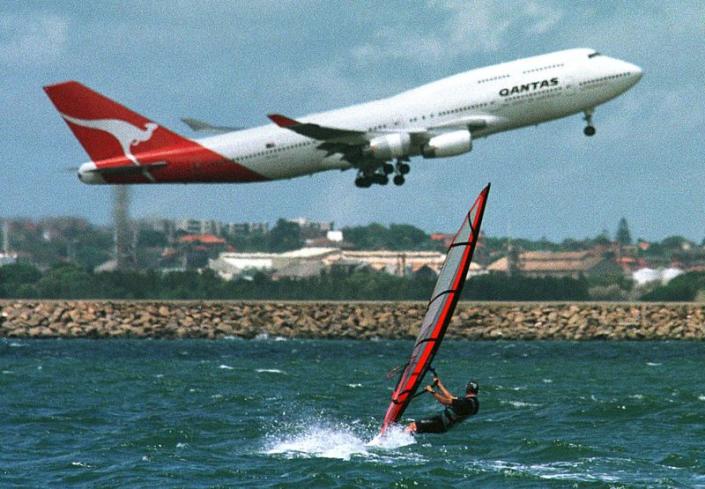 FILE PHOTO: A windsurfer on Sydney's Botany Bay heads towards the Sydney Airport runway as a Qantas Boeing 747 p..