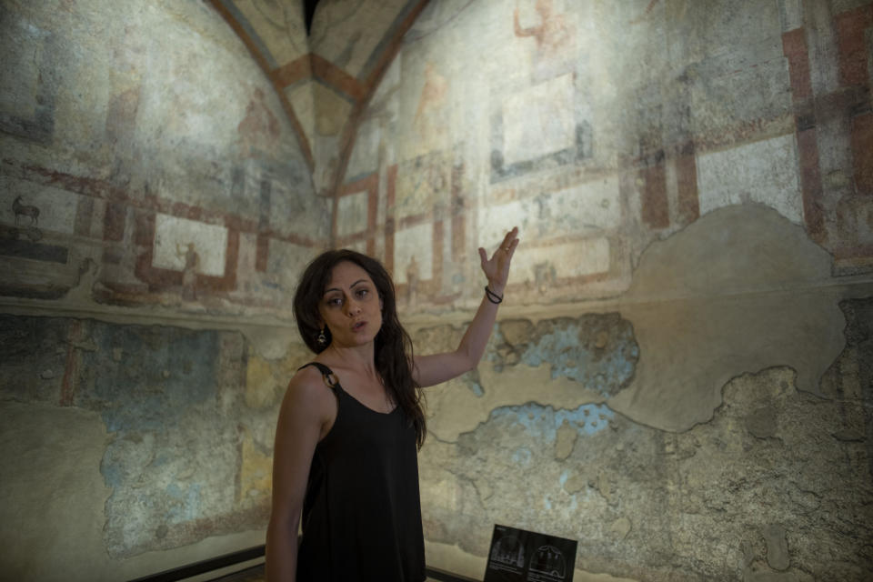 Archaeologist Silvia Fortunati describes to journalists the frescoes coming from the sacellum, a small votive chapel, of a two-story home, or "Domus," dating from around 134-138 AD that was partially destroyed to make way for the construction of the Caracalla public baths, which opened in 216 AD, are on display at the Caracalla archaeological park in Rome, Thursday, June 23, 2022. The frescoed ceiling and walls of a domestic temple honoring Greco-Roman and Egyptian religious deities and believed to have belonged to a wealthy merchant family were first discovered in the mid-19th century about 10 meters (yards) underneath the current ground level of the baths, had been briefly exhibited but has been closed to the public for 30 years. (AP Photo/Domenico Stinellis)