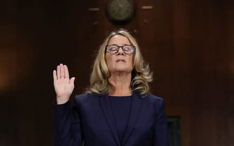 Christine Blasey Ford is sworn in with her hand raised before testifying - Credit: Win McNamee/Getty Images