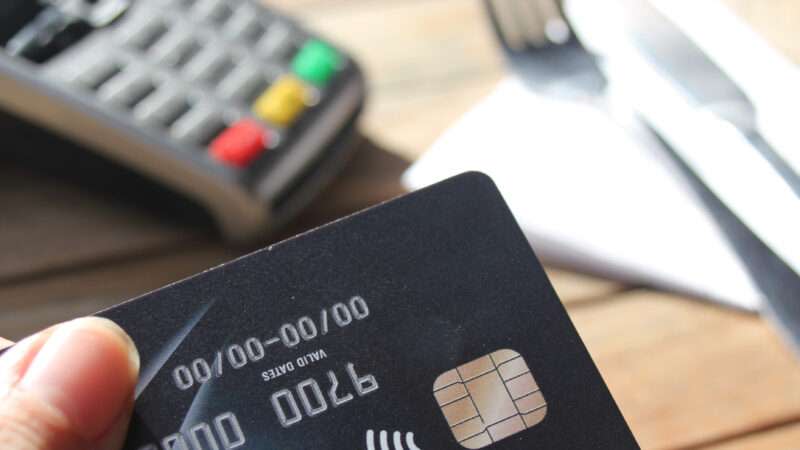 Close-up of a credit card about to be used at point of sale.