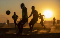 FILE - In this Aug. 19, 2020 file photo, people play soccer on a dusty field in Soweto, South Africa, The country's success in bringing its first wave of COVID-19 under control has allowed it to almost fully reopen the economy, while monitoring for signs of a second surge, says the government's chief medical advisor. (AP Photo/Themba Hadebe,File)