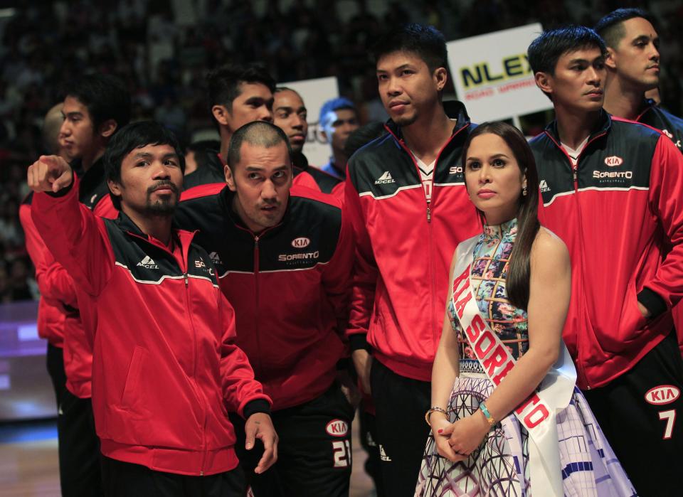 Manny Pacquiao (L), the playing coach of KIA-Sorento, gesture as he joins his teammates during the opening of the 40th Season of the Philippine Basketball Association (PBA) games, against the Blackwater-Elite, in Bocaue town, Bulacan province, north of Manila October 19, 2014. Pacquiao, a congressman and a world renowned boxing champion, ventured into the PBA as a playing coach on Sunday. Manny Pacquiao is scheduled for a title bout against Chris Algieri of the U.S. in Macau on November 22. At right is Pacquiao's wife, Jinky. REUTERS/Romeo Ranoco (PHILIPPINES - Tags: POLITICS SPORT BOXING BASKETBALL)