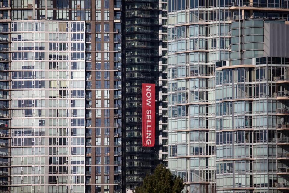 A 'now selling ' banner is pictured on a new condo tower in downtown Vancouver on Jan. 27, 2022. The annual rate of new home construction was up in May of this year, while home sales were slightly down, according to data released separately on Monday by the Canada Mortgage and Housing Corporation and the Canadian Real Estate Association. (Ben Nelms/CBC - image credit)