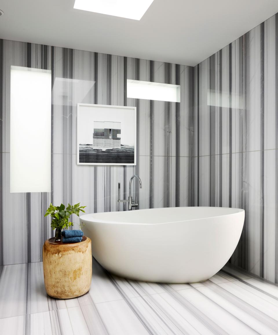 Bold marble slabs can be seen in the primary bathroom, which also includes a Homenature side table and Oliver Michaels photograph.