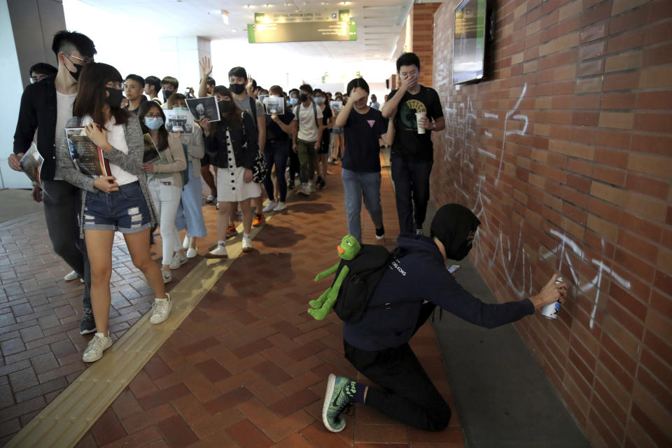 A pro-democracy university student writes on a wall at the campus of the University of Hong Kong, Wednesday, Nov. 6, 2019. The protests began in early June against a now-abandoned extradition bill that would have allowed suspects to be sent for trials in mainland China, which many saw as infringing of Hong Kong's judicial freedoms and other rights that were guaranteed when the former British colony returned to China in 1997. The movement has since grown into calls for greater democracy and police accountability. The Chinese calligraphy reads "Even if only three households remain in Chu (dynasty), it will be Chu that destroys Qin (dynasty)". (AP Photo/Kin Cheung)
