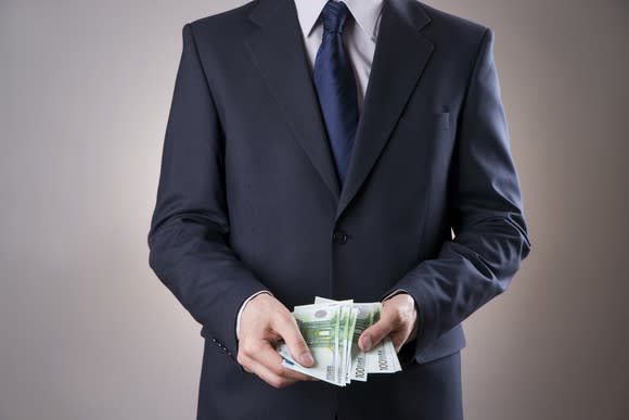 businessman holding wad of bills