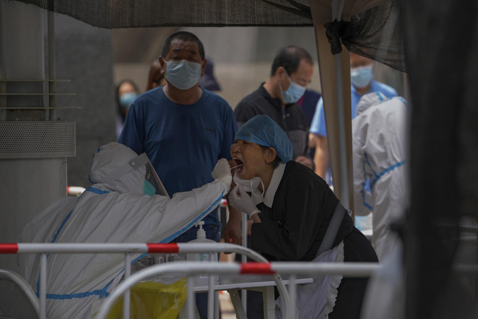 Residents get swabbed at a COVID-19 testing site in the Chaoyang district in Beijing, Tuesday, June 14, 2022. Authorities ordered another round of three days of mass testing for residents in the Chaoyang district following the detection of hundreds coronavirus cases linked to a nightclub. (AP Photo/Andy Wong)