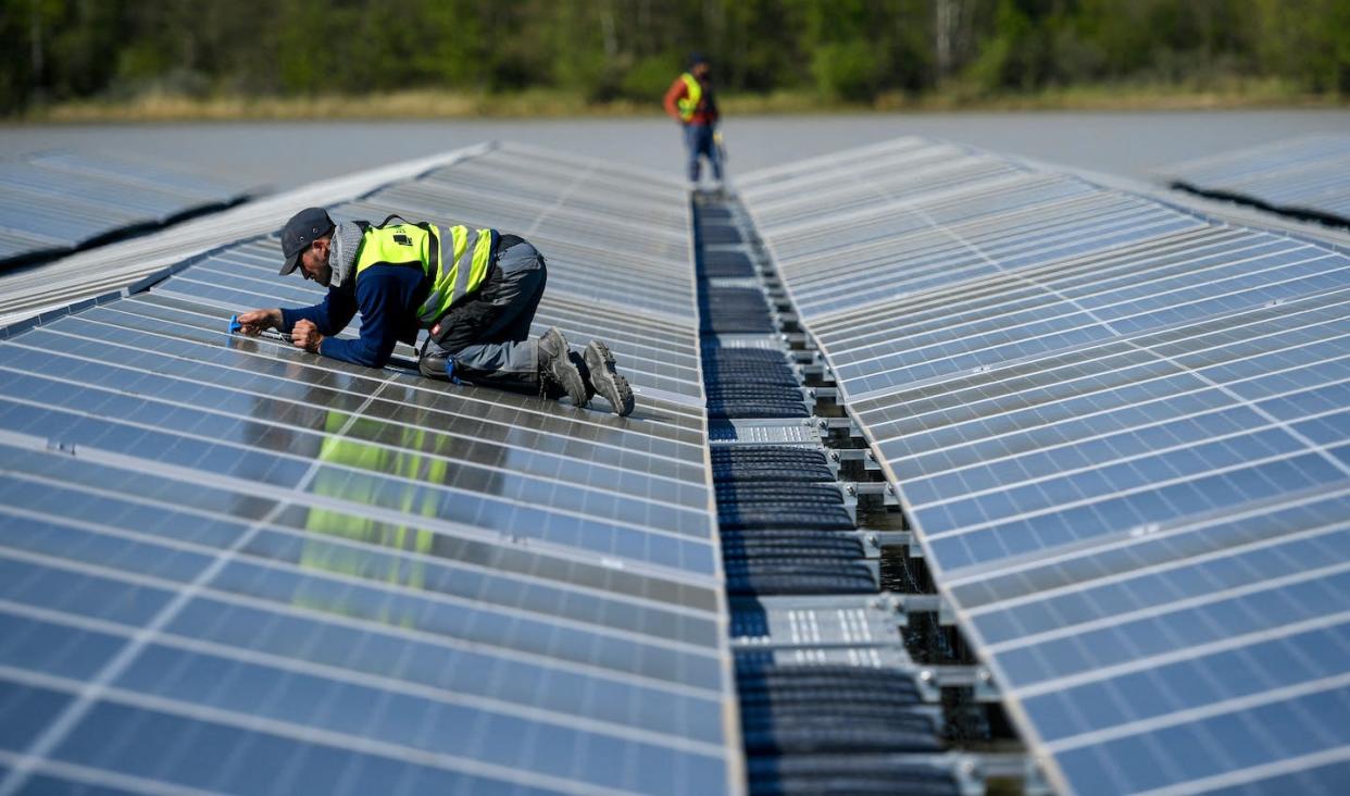 Workers install solar panels for a floating photovoltaic solar plant in Germany in April 2022. <a href="https://www.gettyimages.com/detail/news-photo/worker-fixes-solar-panels-at-a-floating-photovoltaic-plant-news-photo/1240145689?phrase=germany%20solar&adppopup=true" rel="nofollow noopener" target="_blank" data-ylk="slk:Photo by Ina Fassbender/AFP via Getty Images;elm:context_link;itc:0;sec:content-canvas" class="link ">Photo by Ina Fassbender/AFP via Getty Images</a>