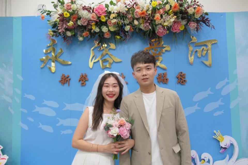 新人謝秉峰和劉曉莉到新營戶政事務所登記結婚，並在戶所的永浴愛河特色結婚牆開心合照。（記者陳佳伶攝）