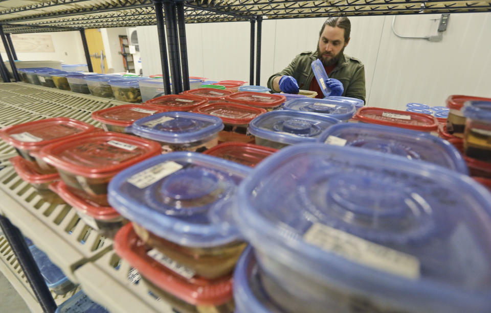 Wet lab conservator, Will Hoffman, replaces artifacts from the USS Monitor into containers at the Mariners Museum in Newport News, Va., Tuesday, Jan. 21, 2014. The museum is facing federal funding shortfalls that threaten to delay the conservation of the USS Monitor artifacts. The museum has seen a steady decline in annual funding from the National Oceanic and Atmospheric Administration amid budget cuts and shifting federal priorities. The turret is in the tank with the green tarp and the steam engine is in the large tank with the black tarp. (AP Photo/Steve Helber)