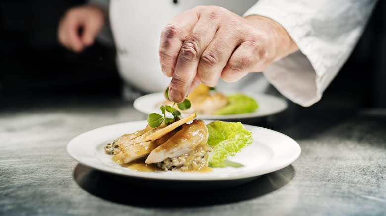 Chef garnishing plate of chicken