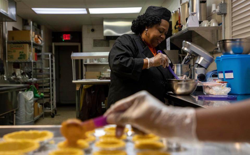 Linda Smith-Cummings, the owner of Soul Amazing LLC, stirs melted butter as she stands inside the North Rosedale Park Community House kitchen in Detroit on Wednesday, Nov. 16, 2022. 