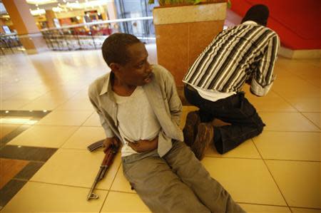 An injured policeman holds on to his wound as his compatriot searches through the Westgate shopping centre for gunmen in Nairobi, September 21, 2013. REUTERS/Goran Tomasevic