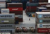 A worker walks amid stacked shipping containers at a commercial port in Vladivostok