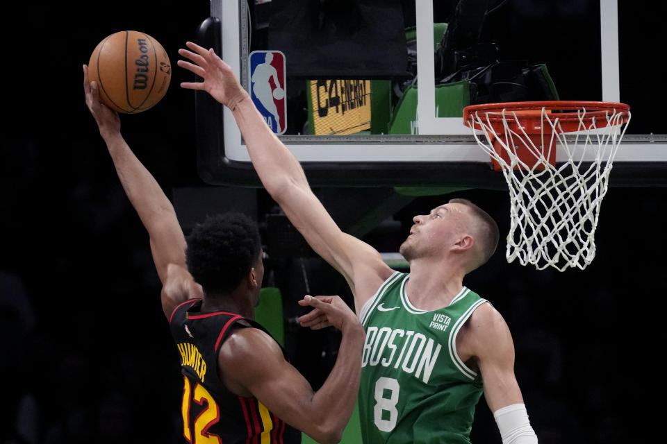 Boston Celtics center Kristaps Porzingis (8) reaches to block a shot by Atlanta Hawks forward De'Andre Hunter (12) during the first half of an NBA basketball game Wednesday, Feb. 7, 2024, in Boston. (AP Photo/Charles Krupa)