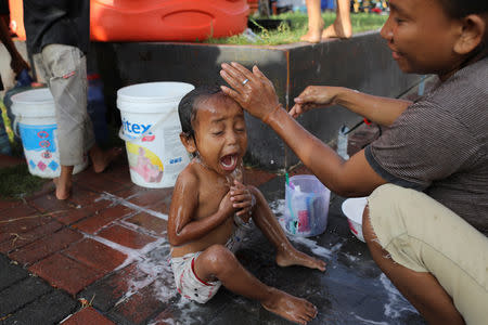 A child reacts while taking a shower at a camp for displaced earthquake and liquefaction victims in Palu, Central Sulawesi, Indonesia, October 12, 2018. REUTERS/Jorge Silva