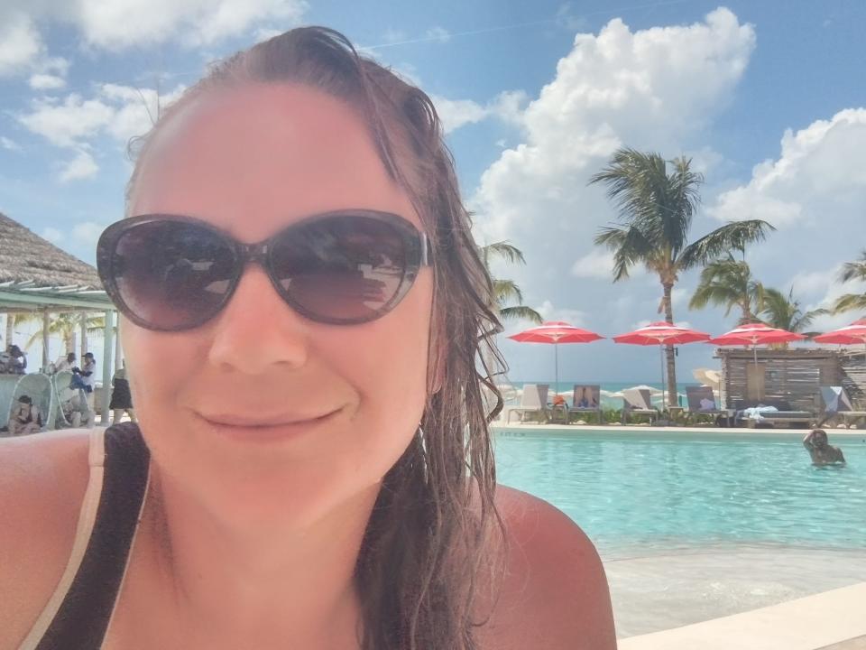 Woman wearing black sunglasses smiling for a selfie in a pool at the Bimini Beach Club