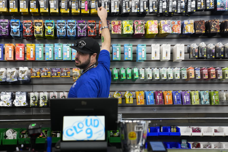 Cloud 9 Cannabis employee Kyler Hollingsworth grabs a product for customers, Saturday, April 13, 2024, in Arlington, Wash. The shop is one of the first dispensaries to open under the Washington Liquor and Cannabis Board's social equity program, established in efforts to remedy some of the disproportionate effects marijuana prohibition had on communities of color. (AP Photo/Lindsey Wasson)