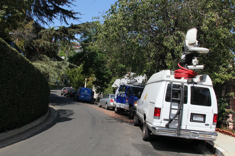 LOS ANGELES, CA - SEPTEMBER 27: News vans are seen at the building (L) where actor Johnny Lewis was found dead on September 27, 2012 in Los Angeles, California. Lewis was found dead September 26, 2012 after apparently falling from the roof of the building he lived in. He is also a suspect in the death of a woman who is thought to have been his landlord and was found dead inside the house. (Photo by David Livingston/Getty Images)