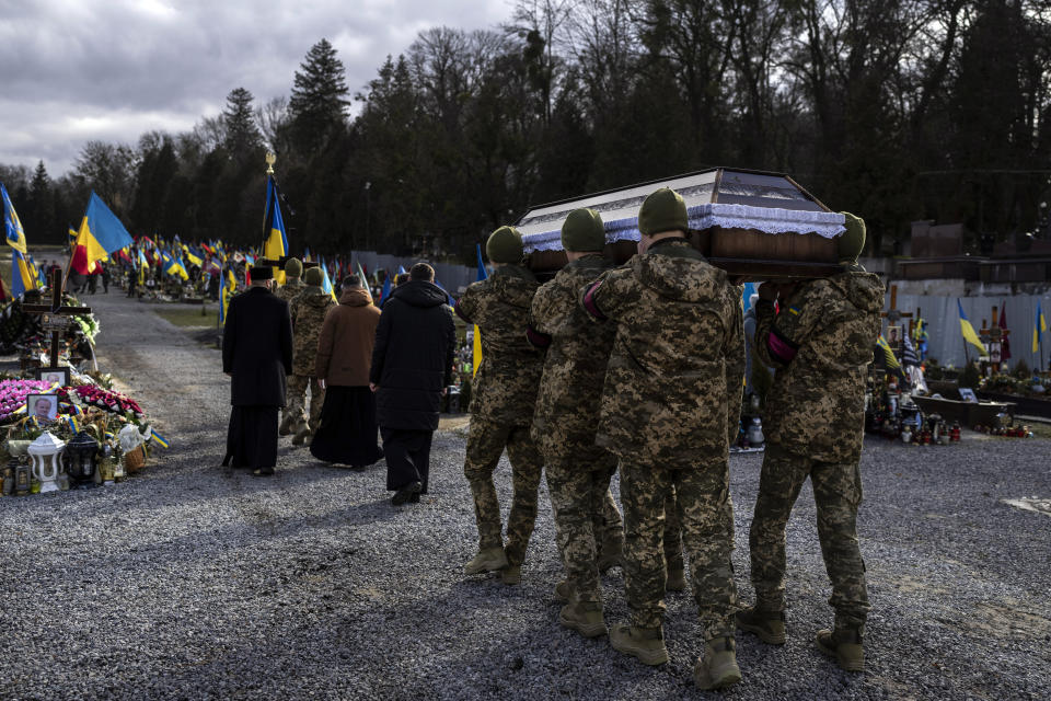 Military servicemen carry the coffin of 20 year-old soldier Vladyslav Belechynskyi, during a funeral at a cemetery in Lviv, western Ukraine,on Wednesday, Feb. 22, 2023. Belechynskyi died near Bakhmut, on Feb.16. (AP Photo/Petros Giannakouris)