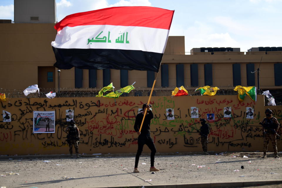 A supporter of Iraqi Shiite armed group popular mobilisation forces carries the Iraqi national flag in front of the US Embassy in Baghdad, Iraq.