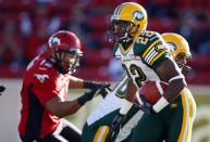 Edmonton Eskimos' Joe Burnett, centre, runs the ball during first half CFL pre-season football action against the Calgary Stampeders in Calgary, Alta., Friday, June 15, 2012. THE CANADIAN PRESS/Jeff McIntosh