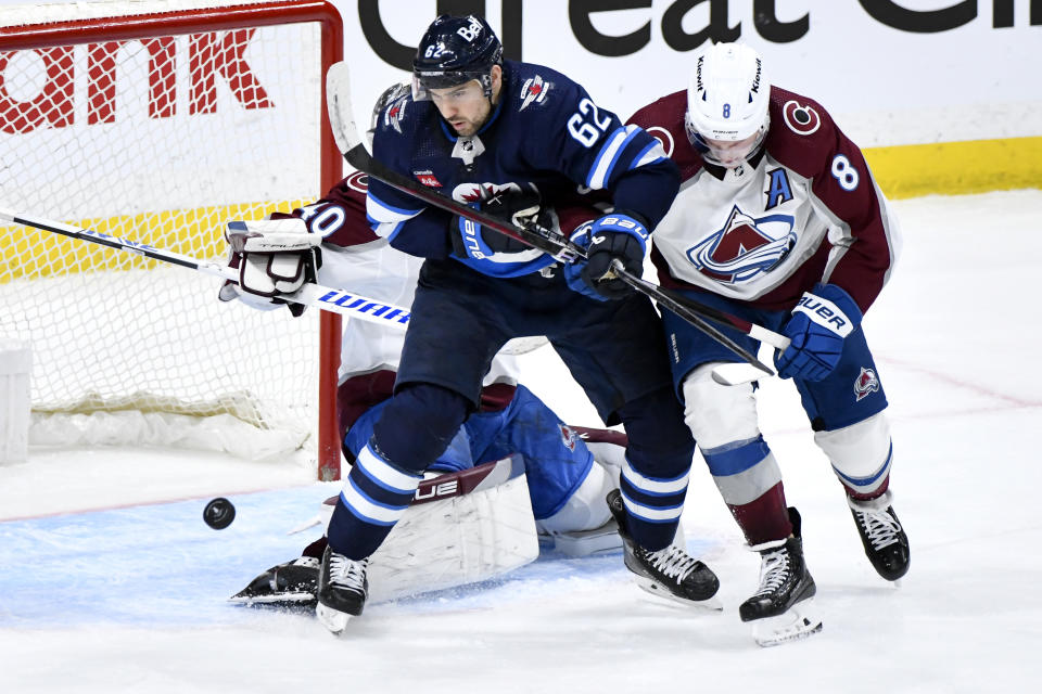 Colorado Avalanche's Cale Makar (8) and Winnipeg Jets' Nino Niederreiter (62) vie for a rebound during the third period in Game 2 of an NHL hockey Stanley Cup first-round playoff series Tuesday, April 23, 2024, in Winnipeg, Manitoba. (Fred Greenslade/The Canadian Press via AP)