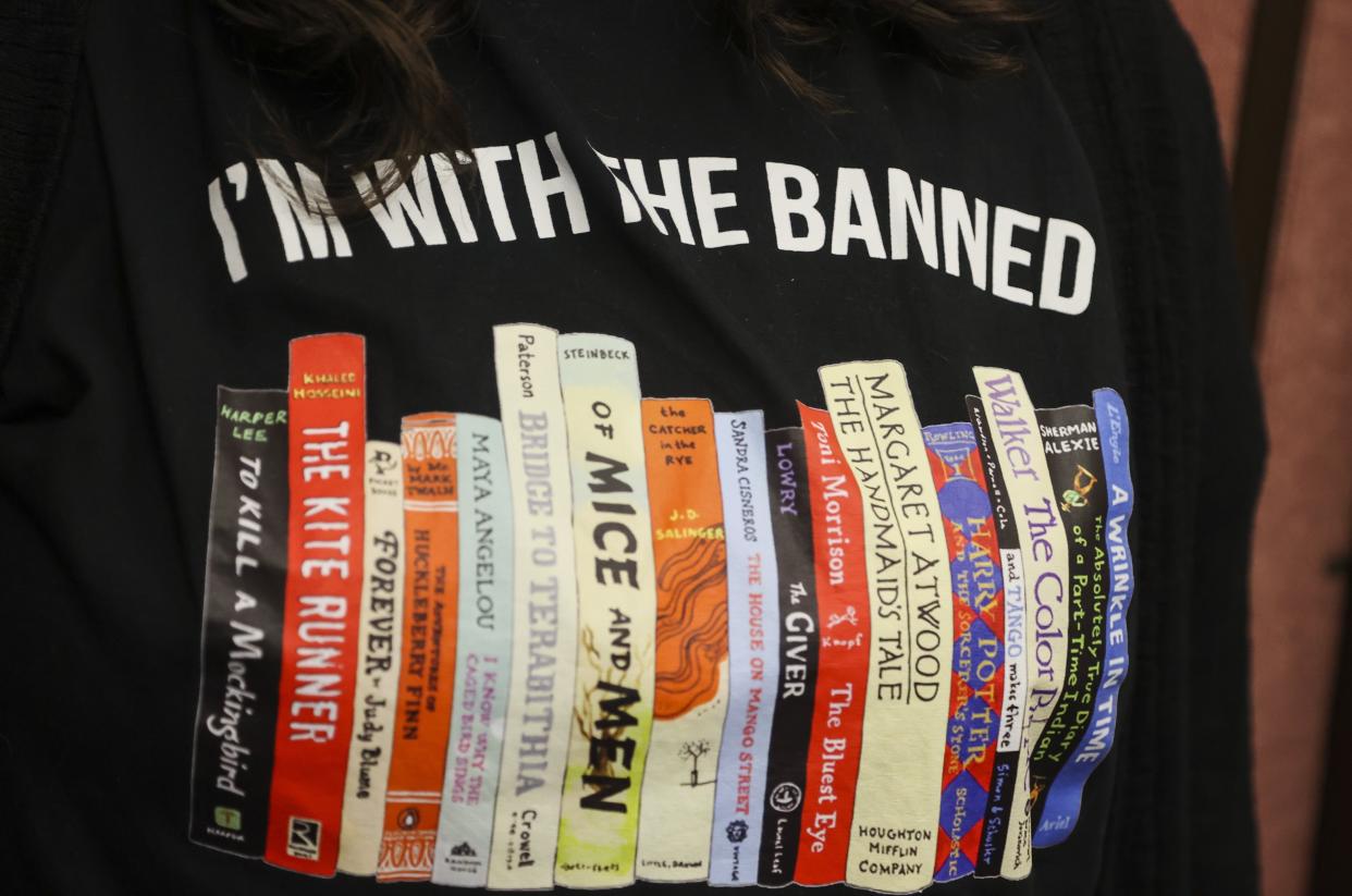 Jennifer Wilson, a Largo High School English teacher, wears a shirt against banning books at the Pinellas County School Board meeting in Largo, Fla., Feb. 14, 2023. In Florida, some schools have covered or removed books under a new law that requires an evaluation of reading materials and for districts to publish a searchable list of books where individuals can then challenge specific titles. (Dirk Shadd/Tampa Bay Times via AP)